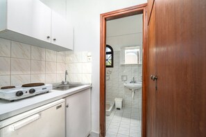 A kitchen with a gas stove, sink, and white cabinets. - Archontiko Studios (Zakynthos)