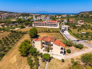 A residential area with a prominent building featuring a red-tiled roof, a balcony, and a small garden area. - Archontiko Studios (Zakynthos)