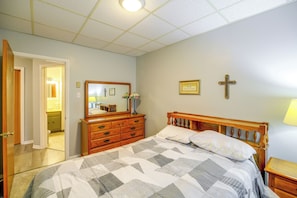 A bedroom with a bed, dresser, and a mirror. There is a door leading to another room. - Sunny Welch Apt: Walk to Riverfront Park! (Welch)