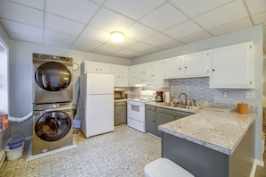 A compact kitchen with a washing machine, refrigerator, microwave, stove, and sink. - Sunny Welch Apt: Walk to Riverfront Park! (Welch)