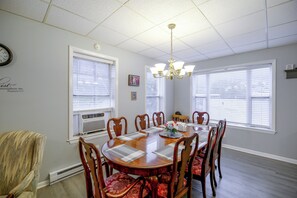 A dining room with a round table, chairs, a chandelier, and windows with blinds. - Sunny Welch Apt: Walk to Riverfront Park! (Welch)