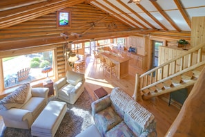 A spacious cabin interior with a dining area, kitchen, and a staircase leading to an upper level. - Waterfront Lake Charlevoix Cabin 8 Mi to Boyne Mtn (Boyne City)