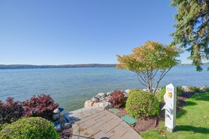 En gångstig som löper längs med sjön, med en bänk, ett träd och en vit elcentral längs vägen.