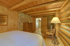 Un intérieur en bois comprenant un lit, une commode, une chaise et une lampe.