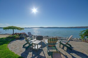 Eine Terrasse am Wasser mit Adirondack-Stühlen und einem Feuerkorb.