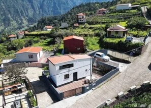 A residential area with houses, a paved road, and a mountain backdrop. - Little Hideaway - São Vicente (Madeira)