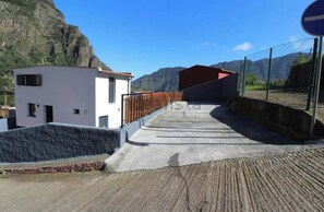 Ein modernes Gebäude mit flachem Dach, einer Betonrampe, die zu einem verschlossenen Eingang führt, und einem Bergpanorama im Hintergrund.