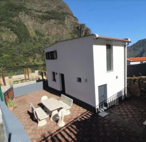 A small white building with a patio area, a table, and chairs. - Little Hideaway - São Vicente (Madeira)