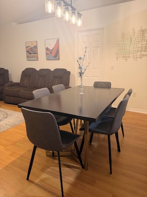 Un comedor con una mesa rectangular, seis sillas y una araña.