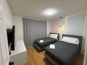 Ein Hotelzimmer mit zwei Betten, einem Fernseher und einem Fenster mit Vorhängen.