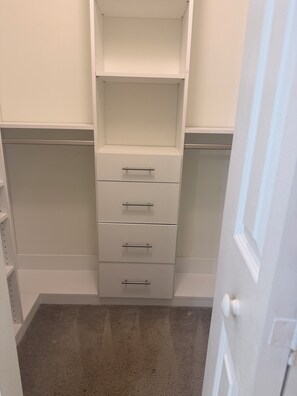 A walk-in closet with open shelves and drawers.
