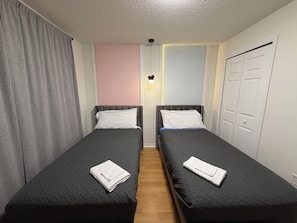 Habitación doble con dos camas individuales, un armario y una lámpara fijada a la pared.