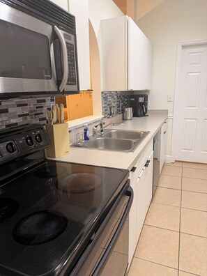 A kitchen with a stove, microwave, sink, and cabinets.