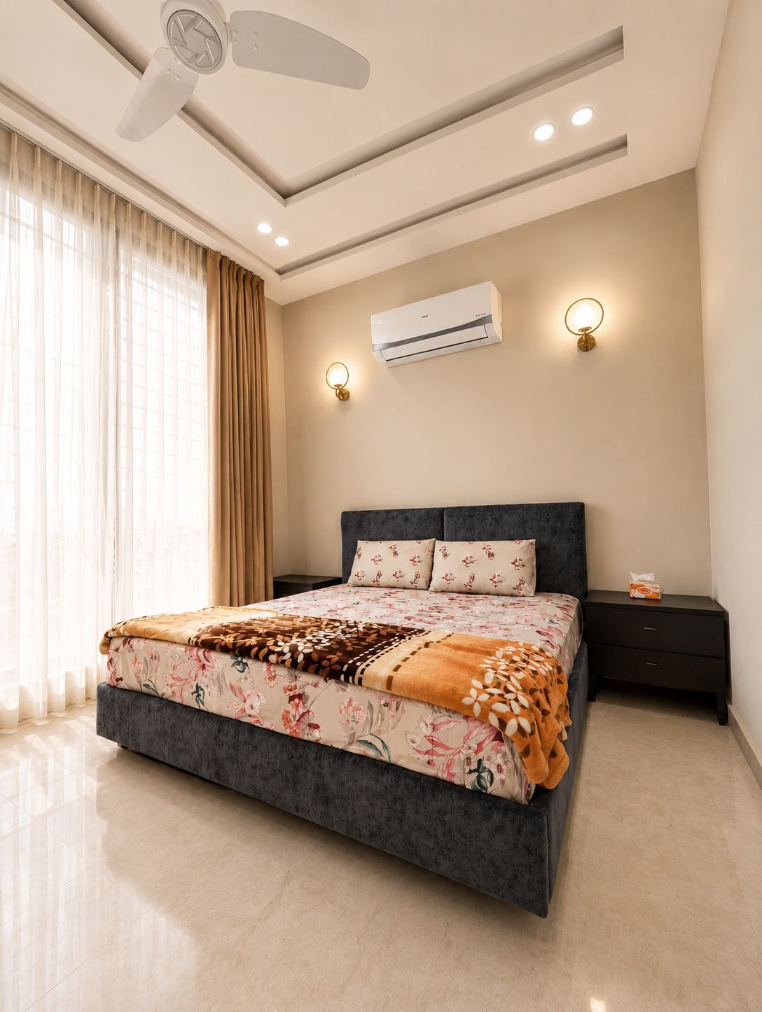 A modern bedroom with a large bed, an air conditioning unit, recessed ceiling lights, and a ceiling fan.
