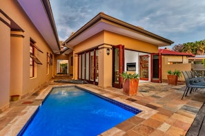 Un immobile residenziale con piscina, un patio coperto e vista sul quartiere circostante.