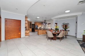 A modern kitchen with a central island, dining area with chairs, and a large mirror. - Luxurious 4-Bedroom Villa with Private Pool in Hartbeespoort (Hartbeespoort)