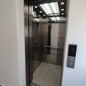 A modern elevator with a metallic interior, a glass door, and a control panel with directional buttons. - Charming Bayahíbe Apartment Comfort Pool, Beach Access (Bayahíbe)