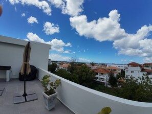 A balcony with a view of a residential area, a chair, and a potted plant. - Charming Bayahíbe Apartment Comfort Pool, Beach Access (Bayahíbe)