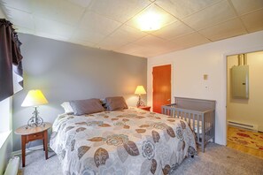 A bedroom with a bed, two bedside lamps, a wooden door, and a radiator. - Historic Welch Retreat! Ride, Hike & Explore (Welch)