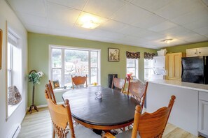 A dining area with a round table, chairs, a window with a view, and kitchen appliances. - Historic Welch Retreat! Ride, Hike & Explore (Welch)