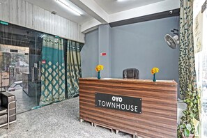 A reception desk labeled 'OYO TOWNHOUSE' with a modern design, a glass door entrance, and a view of the outside. - Signature Hotel Noida-62 (Noida)