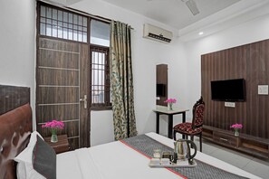 A hotel room with a bed, a desk, a chair, a TV, and a window with curtains. - Signature Hotel Noida-62 (Noida)