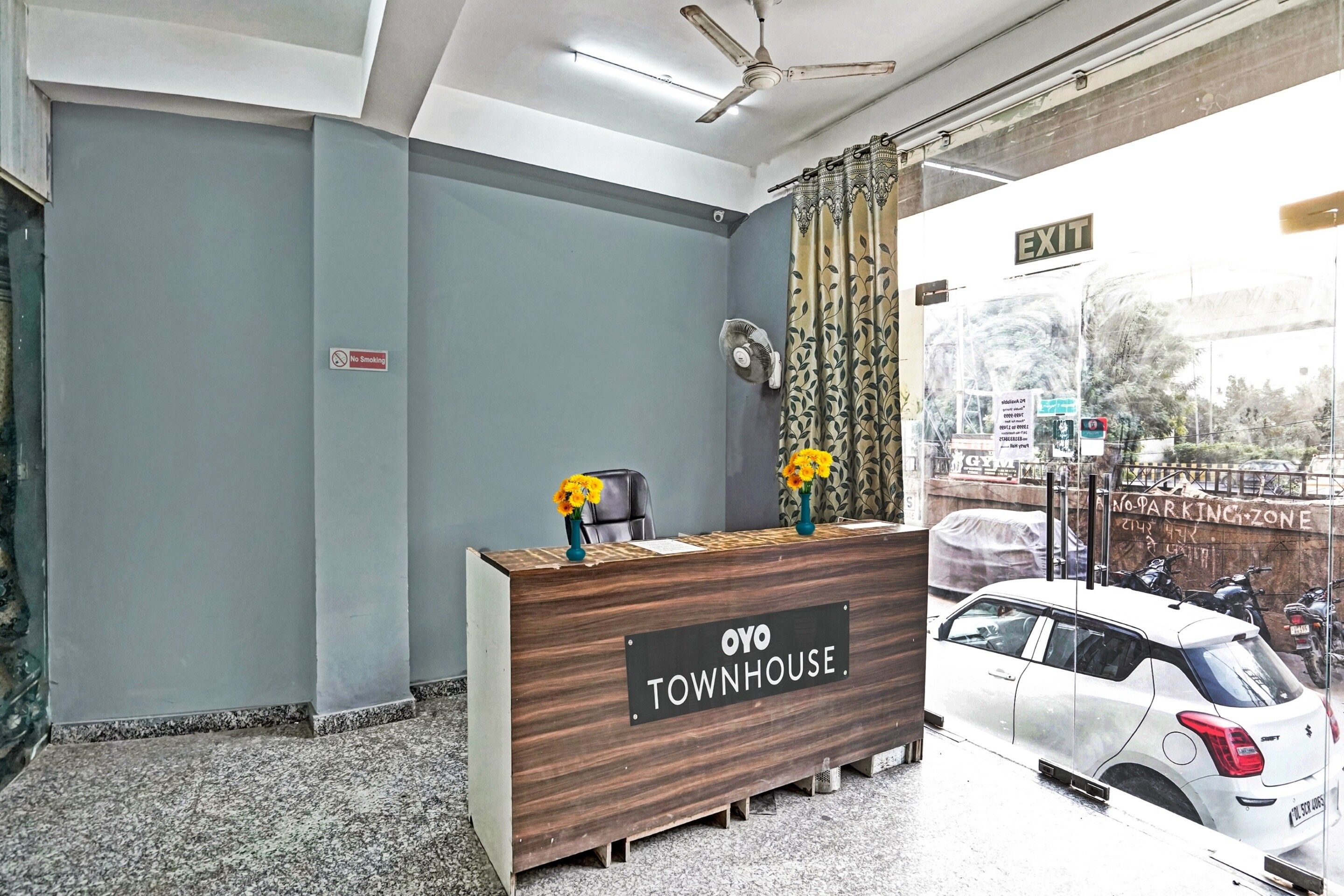 Un comptoir d’accueil avec une enseigne indiquant « OYO TOWNHOUSE » et un panneau « Interdiction de fumer » sur le mur.