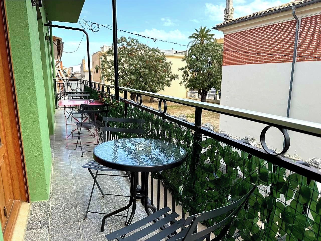 Un balcone con area salotto esterna, comprensiva di tavoli e sedie, e un parapetto.
