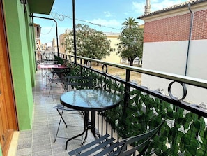 A balcony with outdoor seating, including tables and chairs, and a railing.