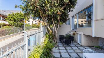 Zona residenziale con patio lastricato, mobili da esterno e un albero.