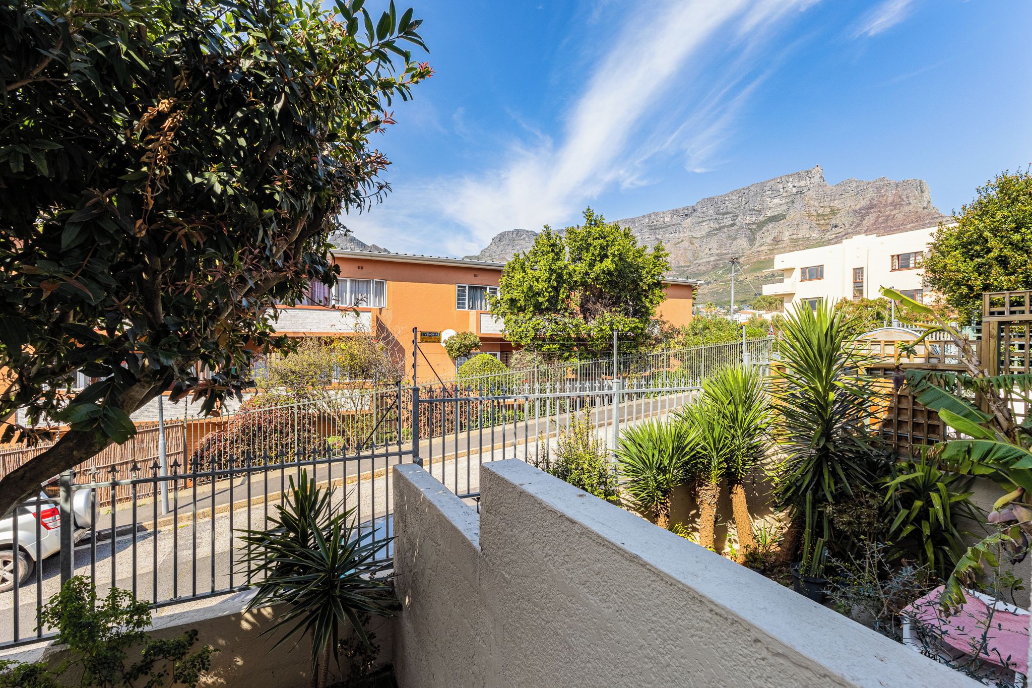 Zona residencial con una calle, una valla y casas con balcones.