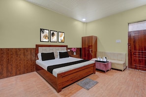 A bedroom with a wooden bed, a wooden wardrobe, a sofa, and a small table with a vase of flowers. - Hotel O Takrohi Hospital Road (Lucknow)