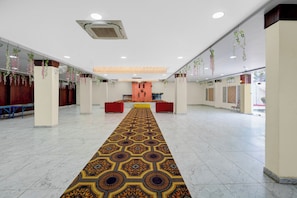 Un vestíbul ampli amb un terrapatró, zones d'estar i plantes penjants.