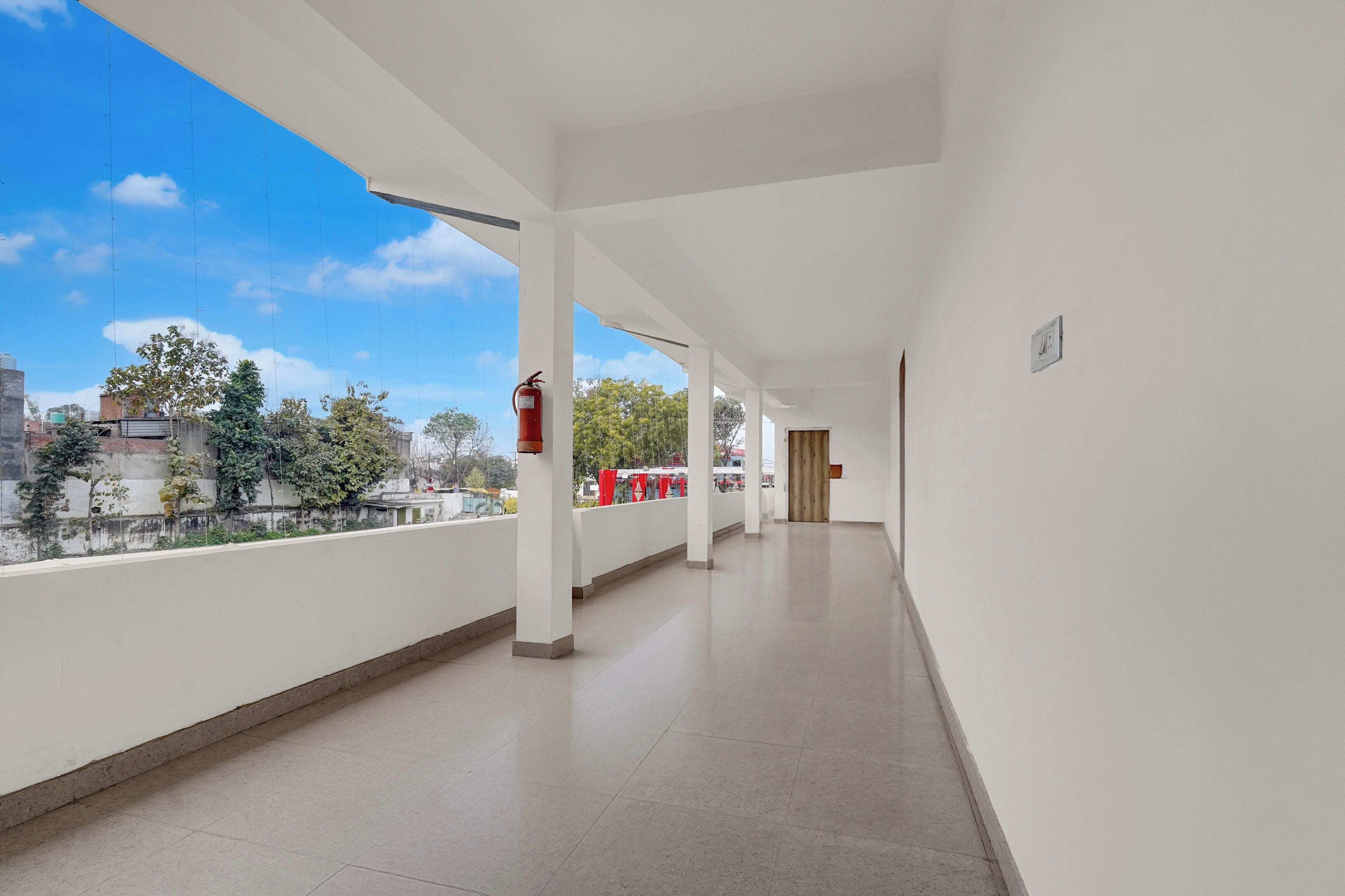 A corridor with white walls and a tiled floor, leading to a door at the end.
