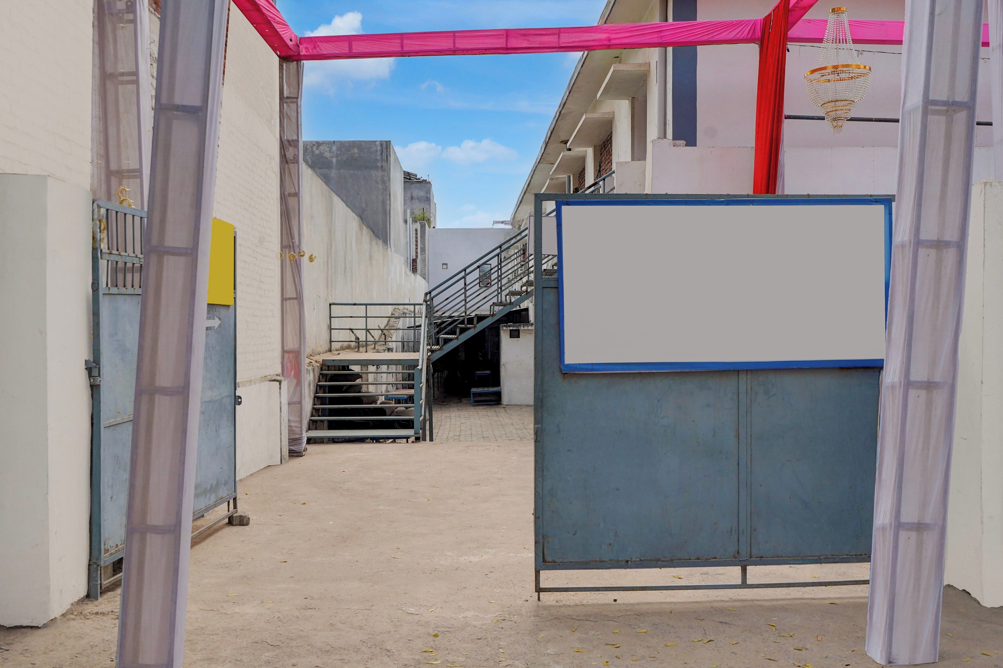 An industrial-style corridor with a metal gate, a staircase, and a whiteboard on a wall.