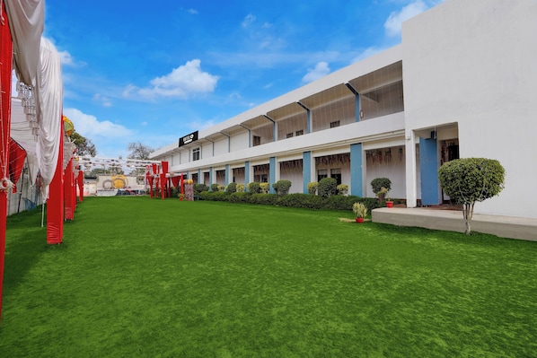 A hotel with a covered outdoor area, a lawn, and a building with a sign that reads 'HOTEL'. - Hotel O Takrohi Hospital Road (Lucknow)