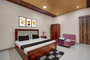 A modern bedroom with a wooden bed, a wooden wardrobe, a pink sofa, and three framed artworks on the wall. - Hotel O Takrohi Hospital Road (Lucknow)