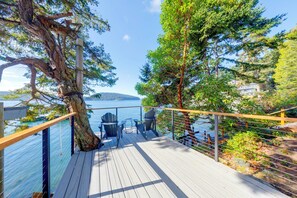 A deck with chairs and tables overlooking a body of water, surrounded by trees. - Deception Pass Waterfront: Salish Sea Serenity (Anacortes)