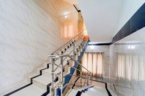 Un escalier moderne avec une rampe en métal, des murs en marbre et une plante en pot.