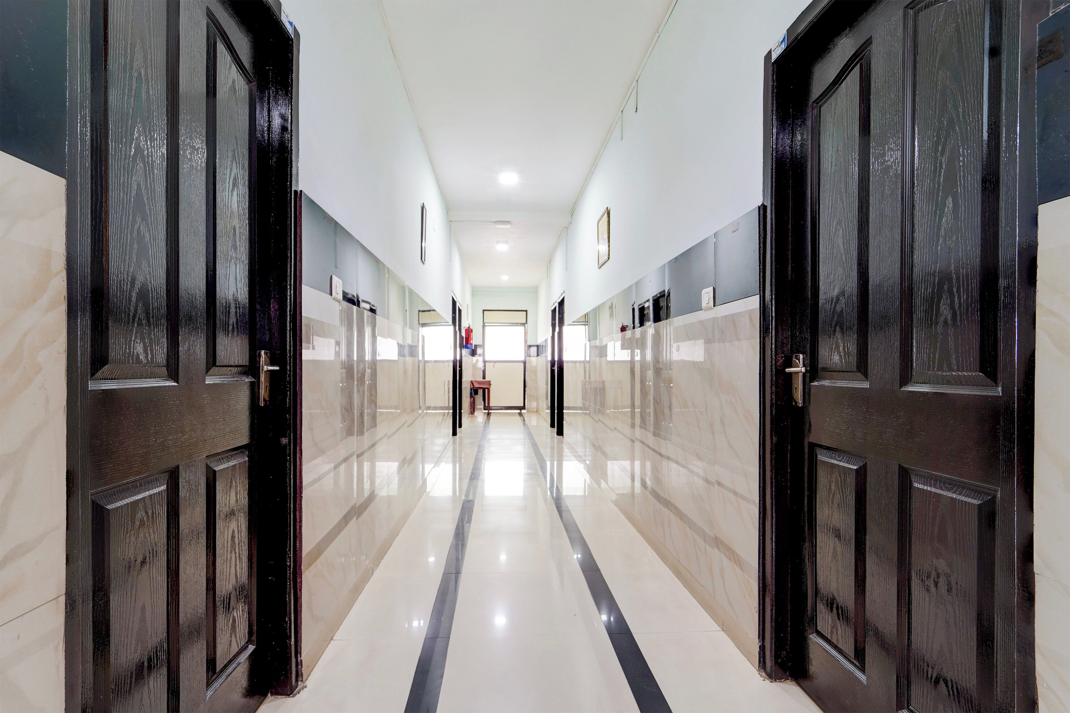 A corridor with doors on both sides, leading to a room with a window.