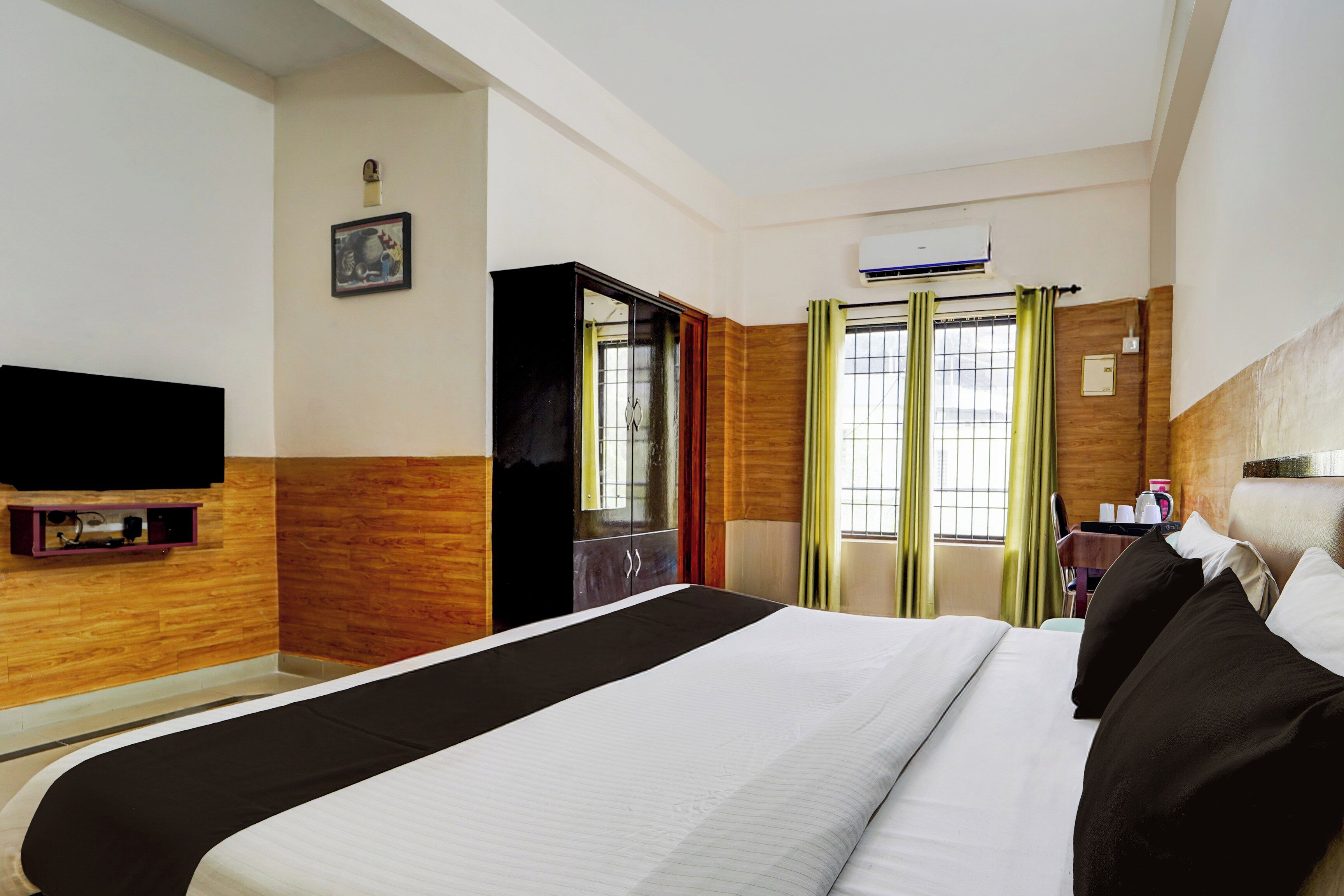 A hotel room with a bed, a TV, a wardrobe, and a window with curtains.