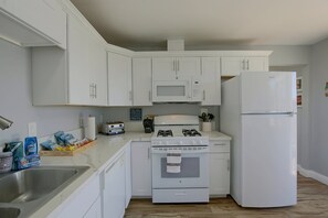 A kitchen with white cabinets, a microwave, a stove, and a refrigerator. - Chic Apt < 5 Mi to SDSU! Private Patio & Views (La Mesa)