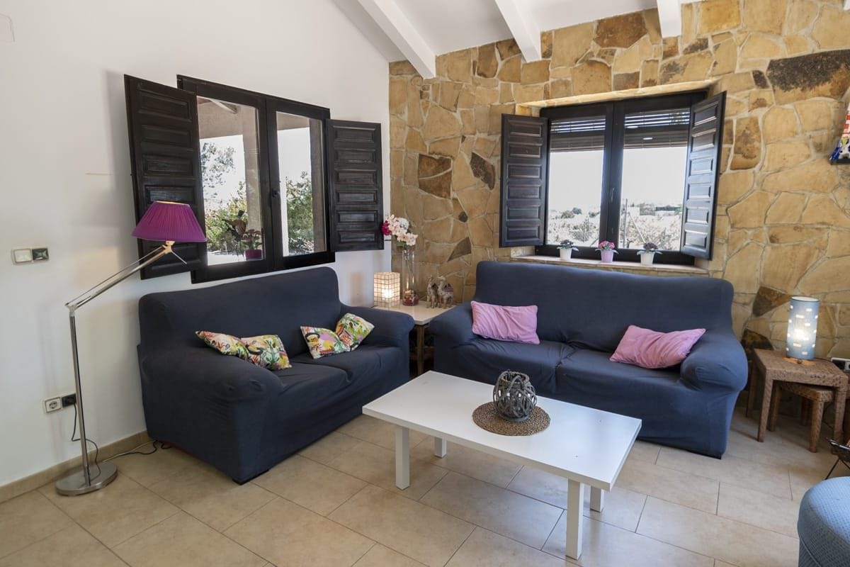A living room with two dark sofas, a white coffee table, and a stone wall.