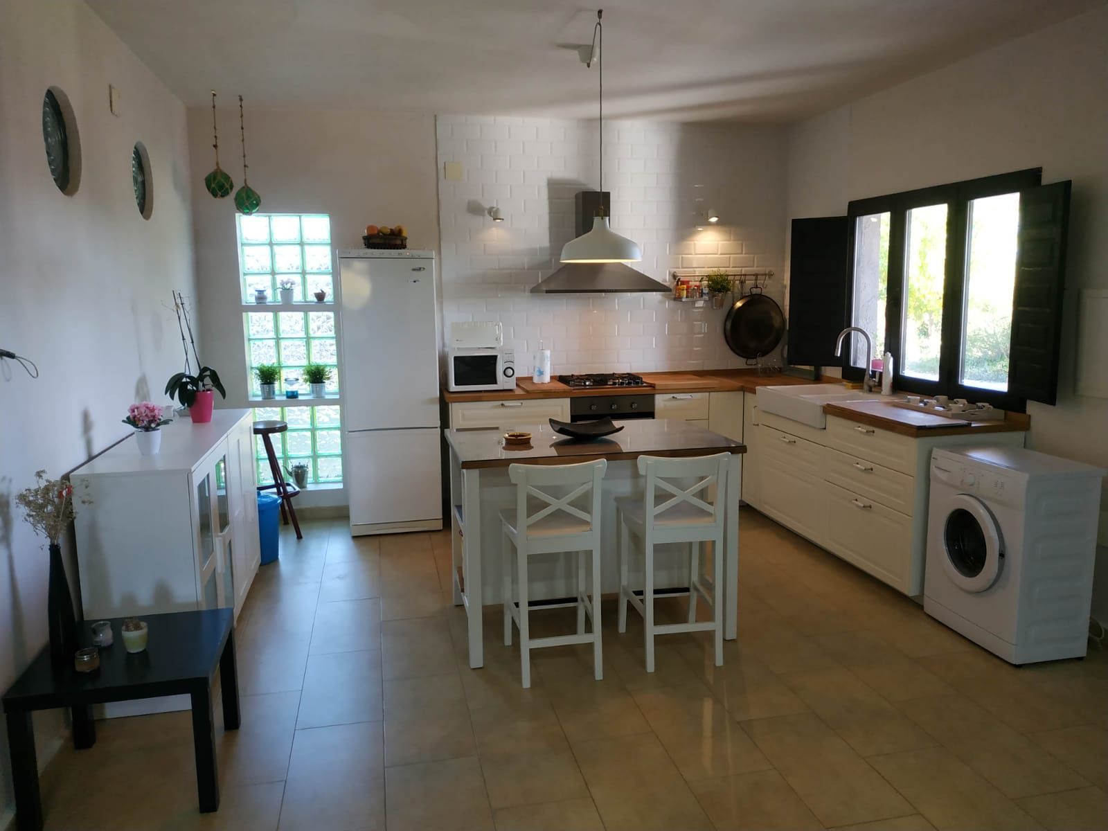 Een moderne keuken met een centraal eiland, een ingebouwde wasmachine en een raam voor natuurlijk lichtinval.