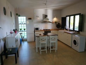 A modern kitchen with a central island, a built-in washing machine, and a window providing natural light. - New Listing (Bullas)