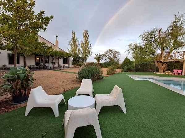 A backyard with artificial grass, a pool, and outdoor furniture.