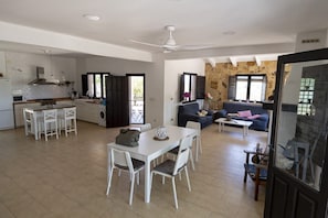 A spacious living area with a dining table, chairs, a sofa, and a coffee table.