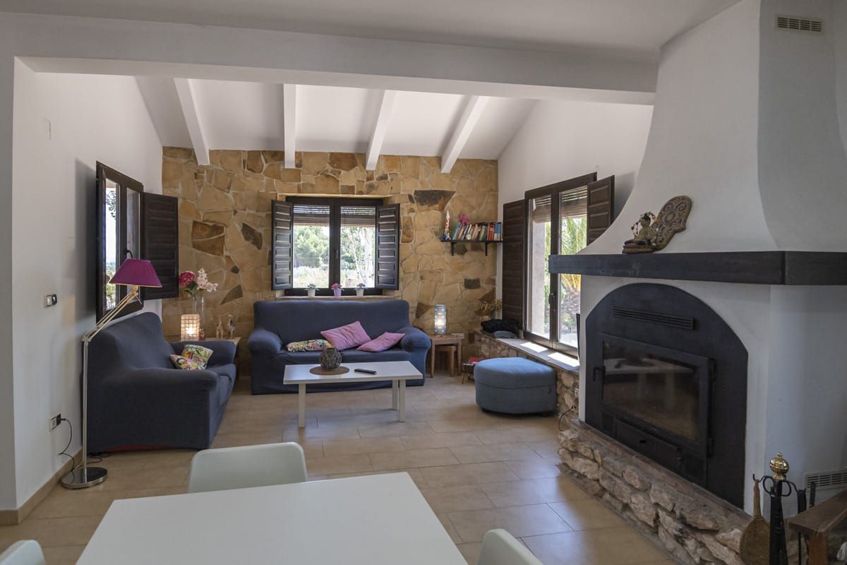 Una sala de estar con pared de piedra, chimenea, sofá, mesa de centro y televisor.