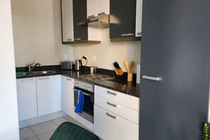 A compact kitchen with a stove, oven, and a sink. - Manhattan Feeling! 2BR, Huge Terrace & Epic Views, 2min walk Bree Street (Cape Town)