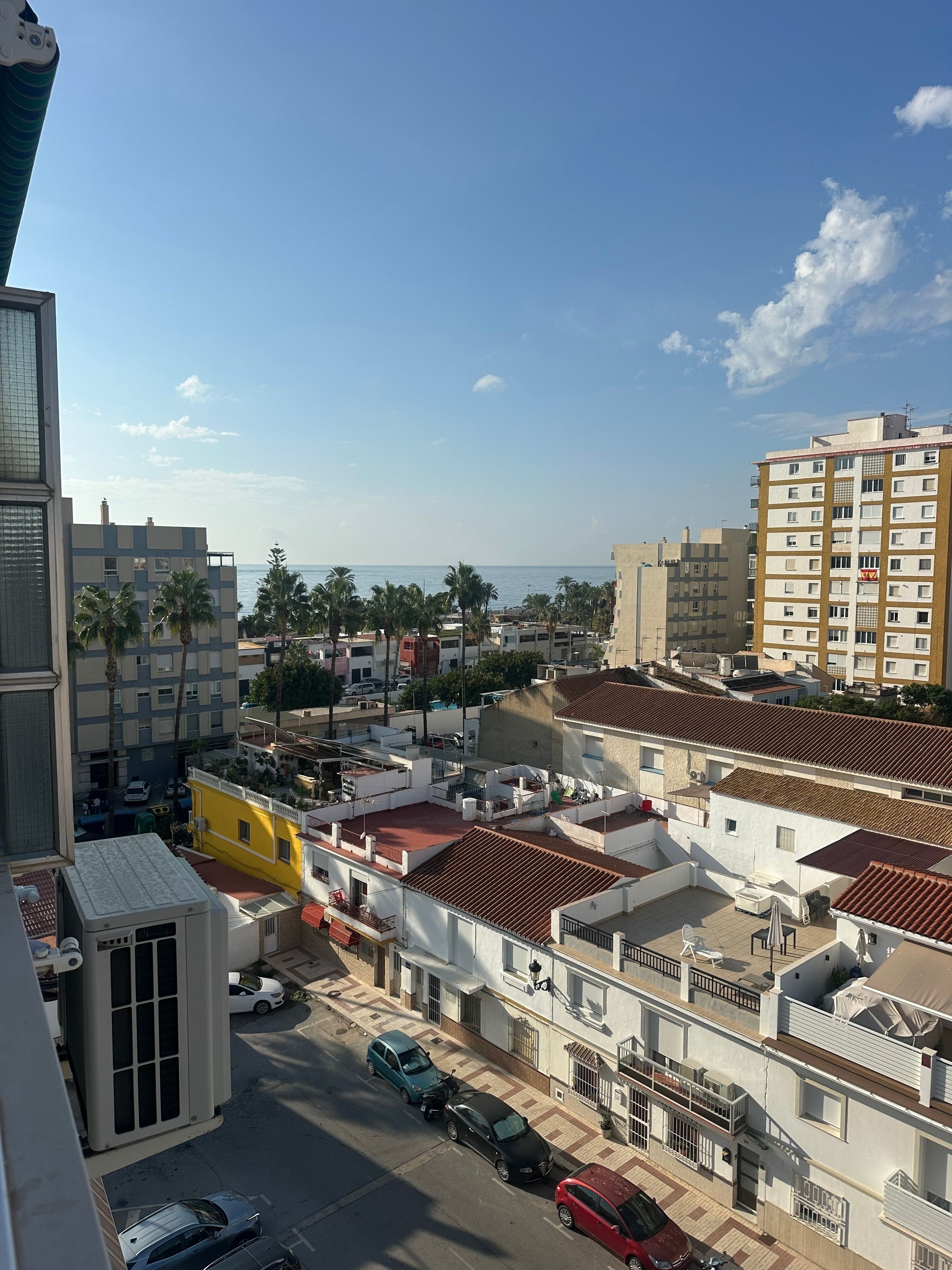 Zona residencial con varios edificios, cielo despejado y vista al mar.